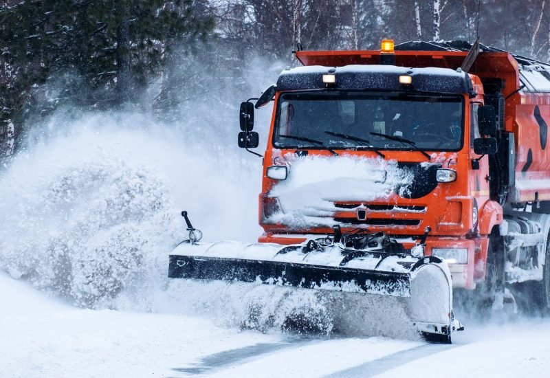 a large orange truck removing piles of snow in the walkway