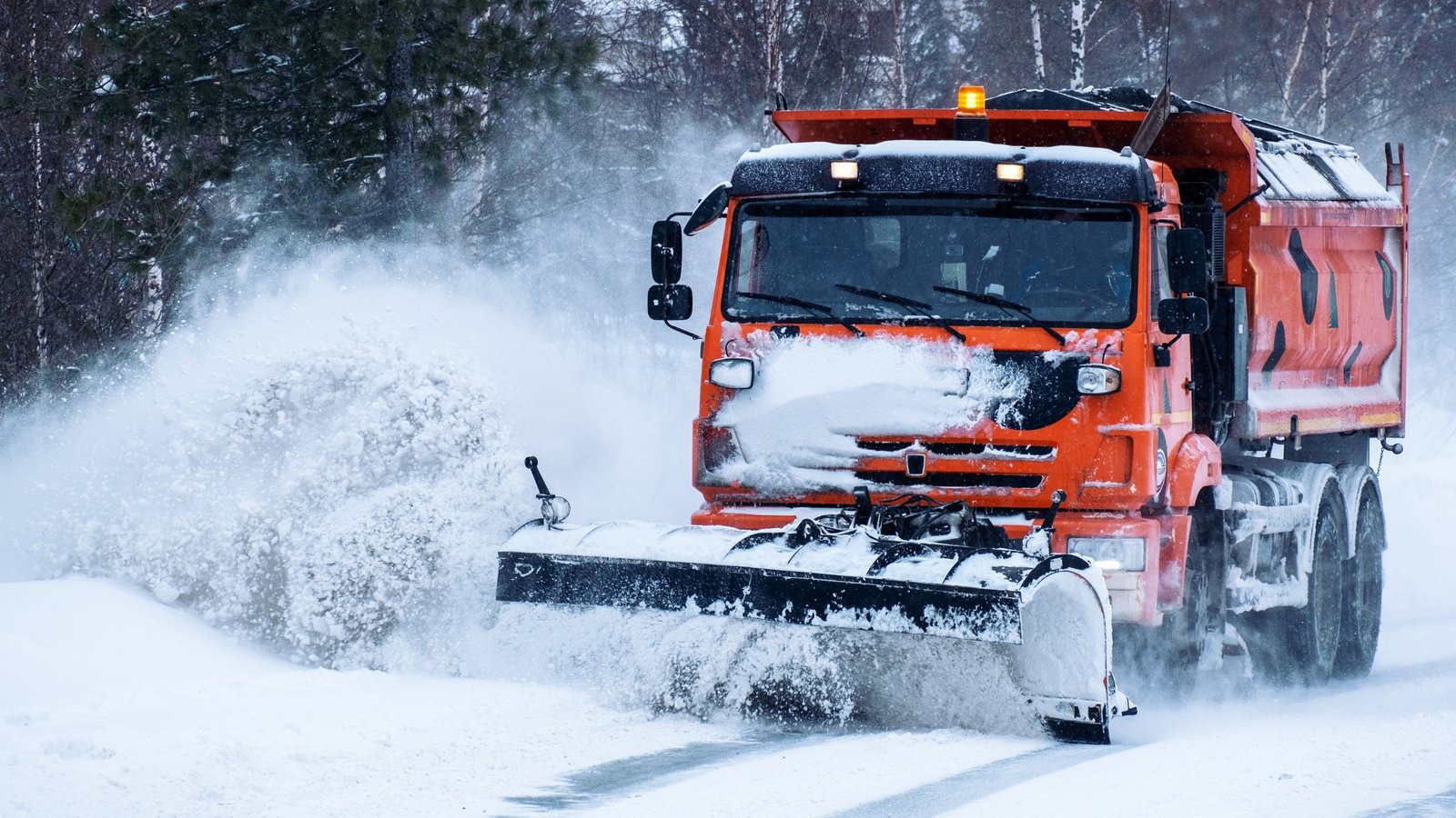 a large orange truck removing piles of snow in the walkway