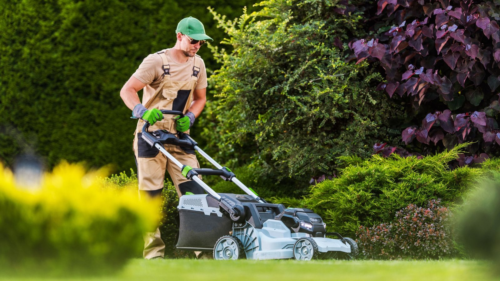 a professional lawn worker wearing a landscaping suit and gloves is doing lawn mowing